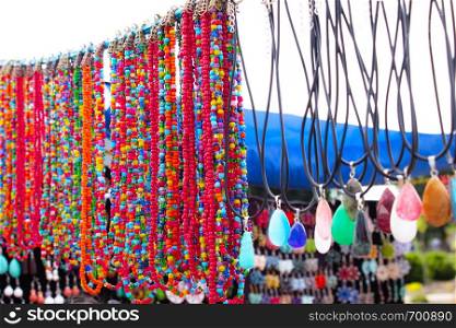 Different necklaces of various shapes and colors with colored stones on a blurred background. Close-up.. Different necklaces of various shapes and colors with colored stones on a blurred background.