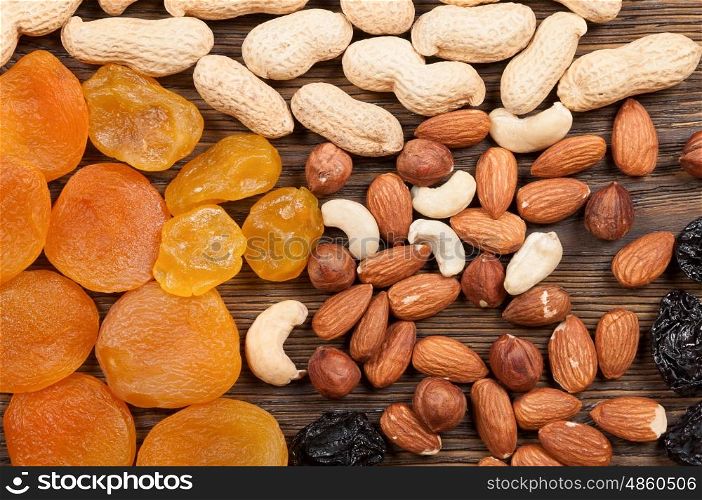 Different nuts and dried fruits on a wooden background. Almond, hazelnut, peanut and apricots.