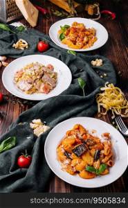 different pasta dishes on wooden with fabric background