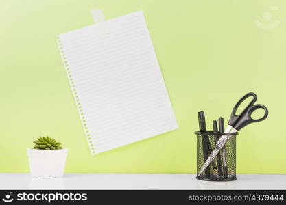 different pens scissors holder near blank paper stucked wall