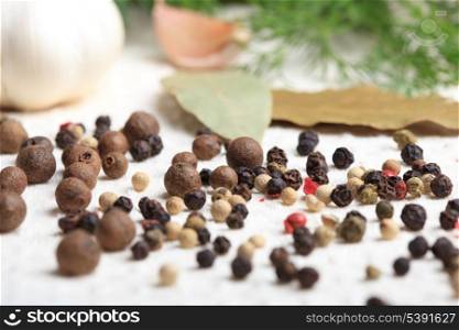 Different peppercorns on white napkin close up