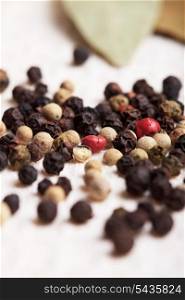 Different peppercorns on white napkin close up
