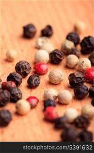 Different peppercorns on wooden table close up