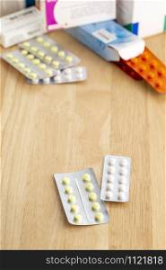 Different pill blisters on a wooden table. Different blisters pack with tablets on a wooden table