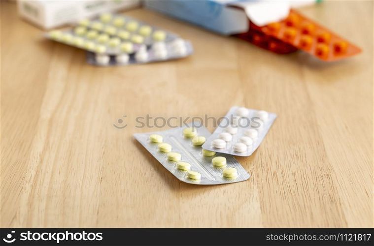 Different pill blisters on a wooden table. Different blisters with tablets on a wooden table