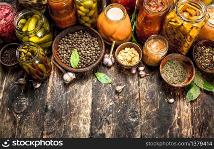 Different preserved vegetables from vegetables and mushrooms in glass jars. On a wooden background.. Different preserved vegetables from vegetables and mushrooms in glass jars.