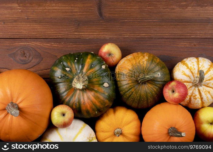 Different pumpkins on a wooden background, autumn theme, texture. Design ideas, top view. Halloween, Thanksgiving day. Pumpkins on wooden background