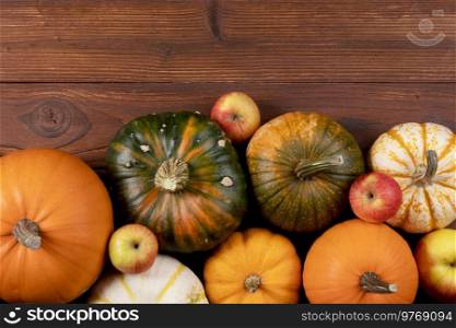 Different pumpkins on a wooden background, autumn theme, texture. Design ideas, top view. Halloween, Thanksgiving day. Pumpkins on wooden background