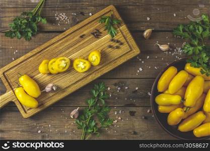 Different raw ripe fresh yellow tomatoes on wooden cutting board. Concept of green house life style and products of subsistence farming, flat lay on dark wooden rustic surface, copy space