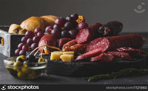 Different sausages with cheese, grapes and olive. Sliced Salami in rustic style.