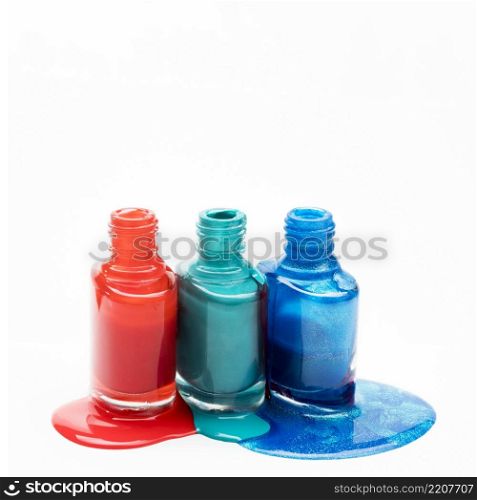 different shades nail polish spilled around three opened bottles