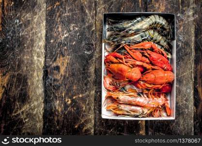 Different shrimps in a box. On a wooden background.. Different shrimps in a box.