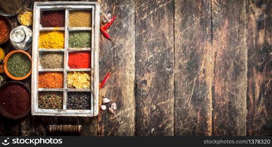 Different spices and herbs in a box. On a wooden background.. Different spices and herbs in a box.