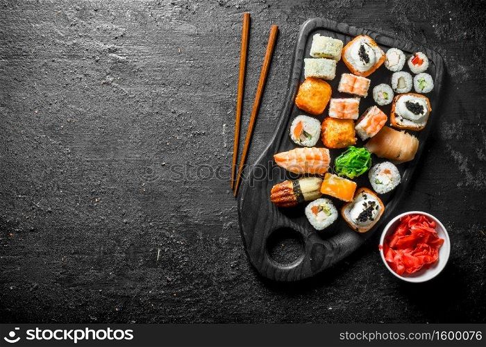 Different sushi rolls on the cutting Board. On black rustic background. Different sushi rolls on the cutting Board.