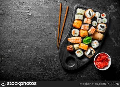 Different sushi rolls on the cutting Board. On black rustic background. Different sushi rolls on the cutting Board.