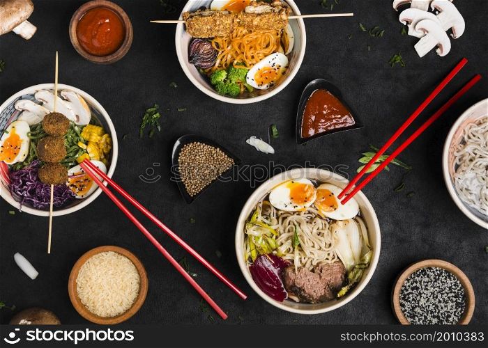 different type asian style ramen noodles with sauce rice sesame seeds black textured backdrop