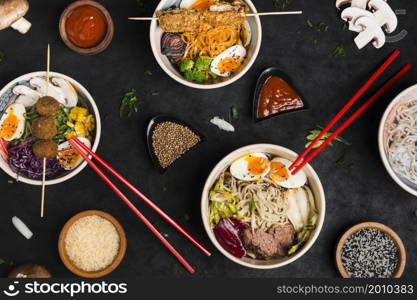 different type asian style ramen noodles with sauce rice sesame seeds black textured backdrop