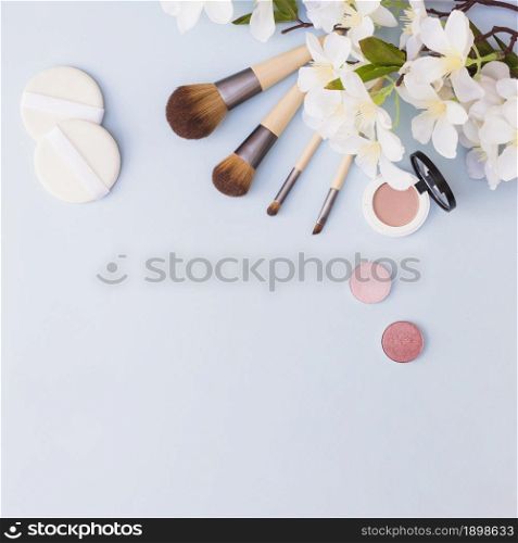 different type makeup brush sponge eye shadow blusher with white flowers blue background. Resolution and high quality beautiful photo. different type makeup brush sponge eye shadow blusher with white flowers blue background. High quality beautiful photo concept