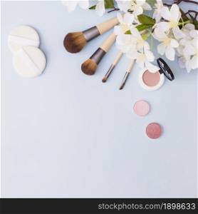 different type makeup brush sponge eye shadow blusher with white flowers blue background. Resolution and high quality beautiful photo. different type makeup brush sponge eye shadow blusher with white flowers blue background. High quality beautiful photo concept