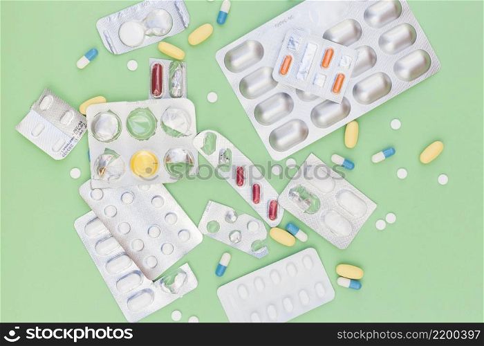 different type medical pills out blister packed against green background