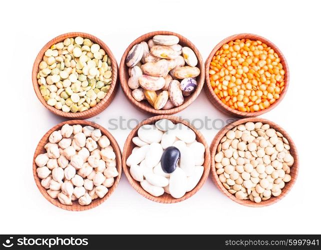 Different types of beans in wooden bowls isolated on white. Types of beans