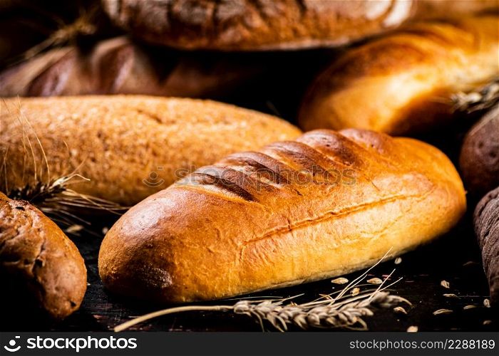 Different types of bread with spikelets. Against a dark background. High quality photo. Different types of bread with spikelets.