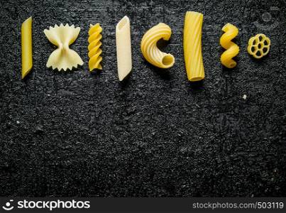 Different types of dry pasta. On black rustic background. Different types of dry pasta.
