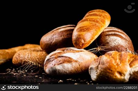 Different types of fresh homemade bread. On a black background. High quality photo. Different types of fresh homemade bread.