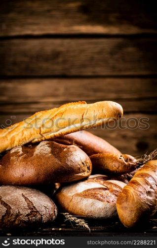 Different types of freshly baked bread. On a wooden background. High quality photo. Different types of freshly baked bread.