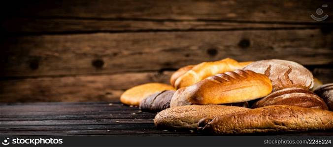Different types of freshly baked bread. On a wooden background. High quality photo. Different types of freshly baked bread.