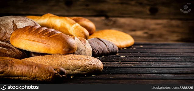 Different types of freshly baked bread. On a wooden background. High quality photo. Different types of freshly baked bread.