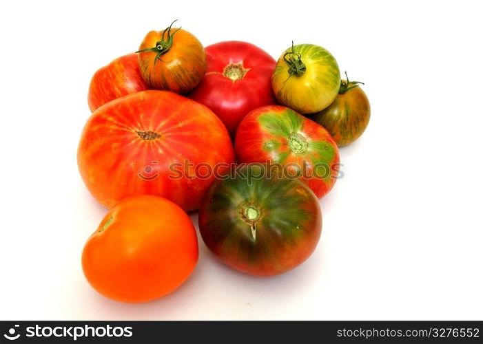 Different types of heirloom tomatoes on a light colored background. Colorful Tomatoes