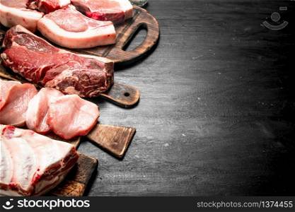 Different types of raw pork meat and beef. On the black chalkboard.. Different types of raw pork meat and beef.