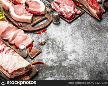 Different types of raw pork meat and beef with spices and herbs. On rustic background.. Different types of raw pork meat and beef with spices and herbs.