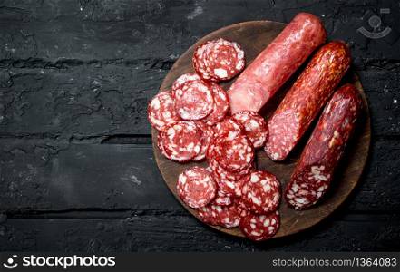 Different types of salami on the Board. On black rustic background.. Different types of salami on the Board.