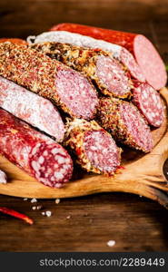 Different types of salami sausage on a cutting board. Against a dark background. High quality photo. Different types of salami sausage on a cutting board.