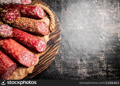 Different types of salami sausage on a cutting board. Against a dark background. High quality photo. Different types of salami sausage on a cutting board.