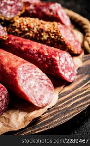 Different types of salami sausage on a cutting board. Against a dark background. High quality photo. Different types of salami sausage on a cutting board.