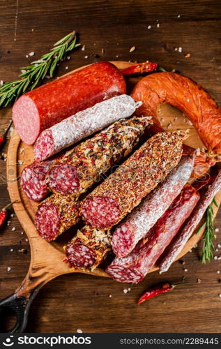 Different types of salami sausage on a wooden cutting board. On a wooden background. High quality photo. Different types of salami sausage on a wooden cutting board.