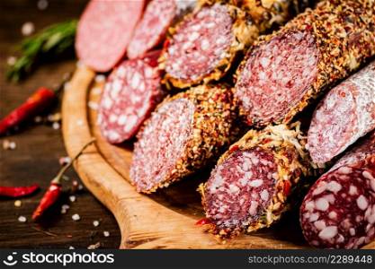Different types of salami sausage on a wooden cutting board. On a wooden background. High quality photo. Different types of salami sausage on a wooden cutting board.