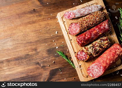 Different types of salami sausage on a wooden cutting board. On a wooden background. High quality photo. Different types of salami sausage on a wooden cutting board.