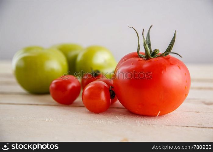 different types of tomatoes on a light wooden background