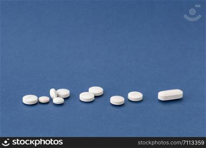 different white drugs on a blue background. different white pills on blue background