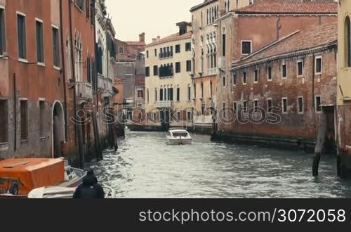 Differrent boats are moving along one of the water canals in Venice, Italy.