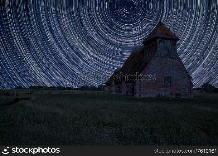 Digital composite image of star trails around Polaris with Ancient Medieval church landscape