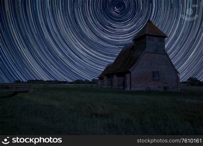 Digital composite image of star trails around Polaris with Ancient Medieval church landscape