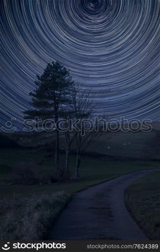 Digital composite image of star trails around Polaris with Beautiful landscape image of farm and trees in Winter