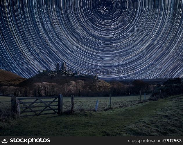 Digital composite image of star trails around Polaris with Stunning landscape of Medieval castle ruins. UK