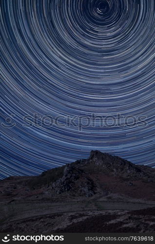 Digital composite image of star trails around Polaris with Stunning Peak District Winter landscape of Ramsaw Rocks