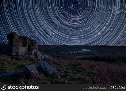 Digital composite image of star trails around Polaris with Stunning vibrant Beautiful landscape image of view from Leather Tor in Dartmoor National Park